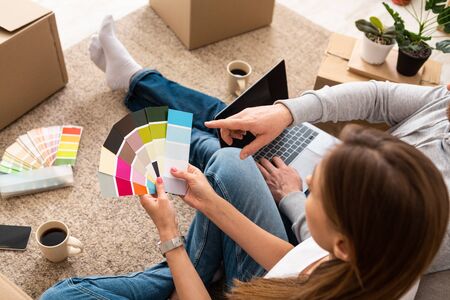 Unrecognizable man showing to a woman color from color palette while holding laptop, repair conceptの写真素材