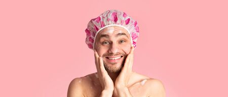Morning shower. Funny guy washing his face and smiling on pink background