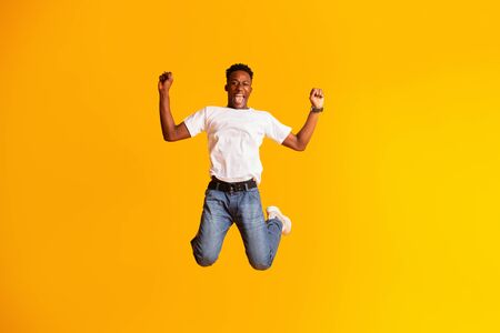 Yes, I did it. Handsome african man jumping against yellow background, copy spaceの写真素材