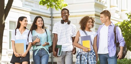 Happy Internatial Students Walking Outside, Going To University Together, Holding Books And Laughing, Panorama With Free Spaceの写真素材