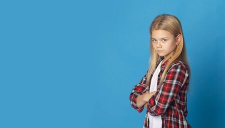 Kids violence. Offended teen boy standing with folded arms, grey panorama background with empty spaceの写真素材
