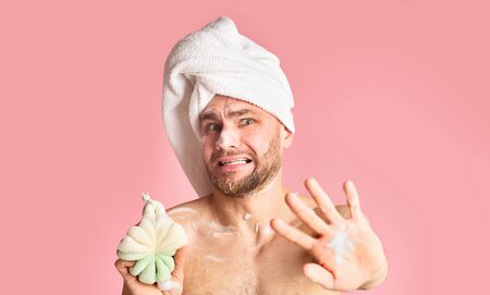 Millennial guy takes a shower and closes with hand on pink background, copy spaceの写真素材