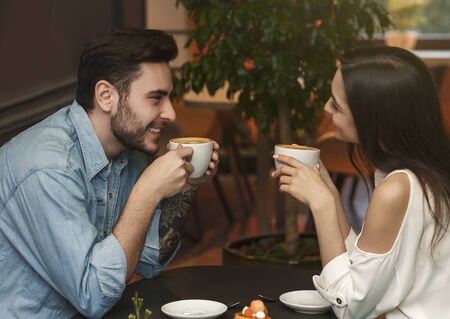 Boyfriend And Girlfriend Talking And Flirting Enjoying Coffee Sitting At Cafe Table Indoor.