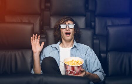 Entertainment concept. Young guy in 3D glasses being scared in movie theater