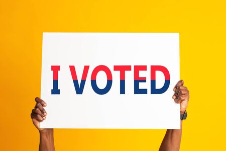 US elections 2020 campaign. African American citizen holding banner with words I VOTED on orange...