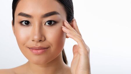 Facial Skincare. Asian Girl Touching Smooth Skin Smiling At Camera Posing Over White Background In Studio. Panorama, Empty Spaceの写真素材
