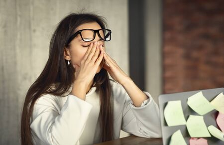 Young freelance woman hard working, taking off glassesの写真素材