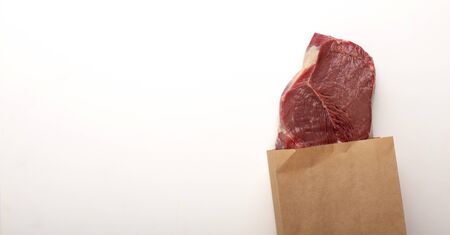 Raw meat in paper bag on gray background, panorama, free spaceの写真素材