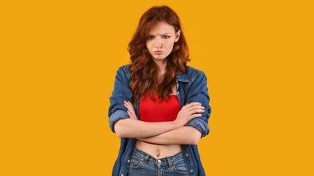 Displeased Girl Sulking Crossing Hands Looking At Camera Posing In Studio Over Yellow Background. Panoramaの写真素材