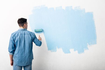 Start of repair. Guy puts first layer of blue paint, back, free spaceの写真素材