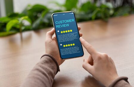 Consumer Showing cell phone with five star for Satisfaction rating on blue screen, blurred background. Customer Experience Conceptの写真素材