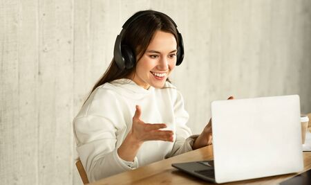 Surprised girl in headphones looking at laptop and points hand at the monitor