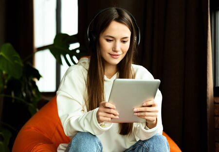 Technology helps work from home. Woman with bluetooth headphones and tablet