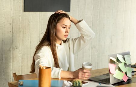 Mistake at work. Freelance woman in shock and holding her headの写真素材