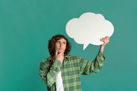 Thinking concept. Dreamy millennial guy with speech bubble deep in thought on color background, space for textの写真素材