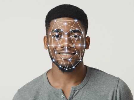 Cyber safety concept. Facial scanning of African American guy in casual clothes on light backgroundの写真素材