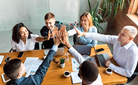 Teamwork. Happy Coworkers Giving High-Five Celebrating Business Success Sitting Together At One Desk In Modern Office.の写真素材