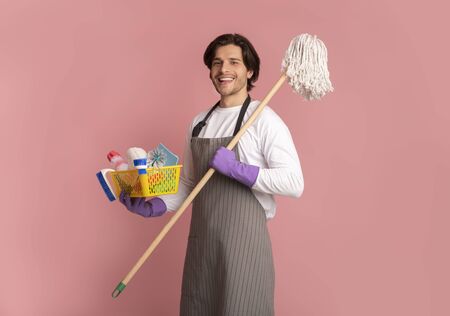 Spring-Clean Service Worker. Portrait Of Happy Man Holding Mop And Bucket With Cleaning Tools, Standing Over Pink Studio Background, Free Spaceの写真素材
