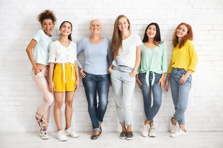 Female Diversity. Multiethnic Women Posing Smiling To Camera Standing Over White Brick Wall...