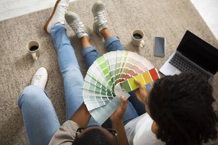 Choice of paint for interior. African american girl and man with color swatch in hands sitting on...