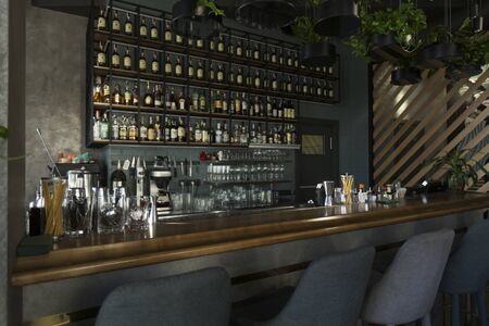 Empty wooden bar counter with bottles of alcohol drinks, bar or cafeteria background for your product display, copy spaceの写真素材