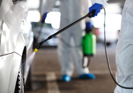 Unrecognizable workers washing car with chemicals, coronavirus concept, covid 19, epidemic