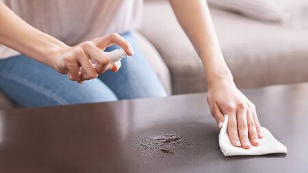 Disinfection at home. Girl wipes table with antiseptic and spongeの写真素材