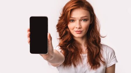 Teen Girl Showing Mobile Phone Empty Screen Advertising App Posing Over White Studio Background....