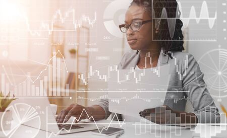 African american businesswoman working with laptop and documents in office, collage with diagrams on virtual screen. Empty spaceの写真素材