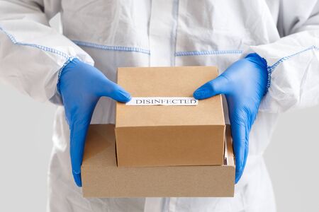 Man holding cardboard boxes in rubber gloves. Delivery service under quarantine