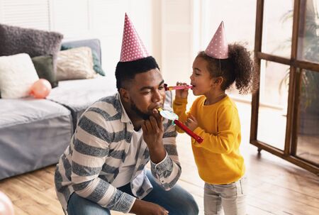 African american dad and daughter blowing in fifesの写真素材