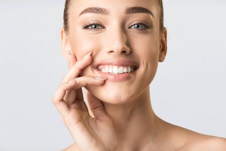 Beauty Concept. Pretty Blonde Girl Touching Lips Smiling To Camera Posing In Studio Over Gray Background. Croppedの写真素材
