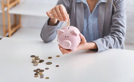Economy during quarantine concept. Business woman puts coins in piggy bankの写真素材