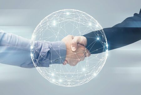 Globalization And Network Technology. Two Unrecognizable Businessmen Handshaking Over Holographic...