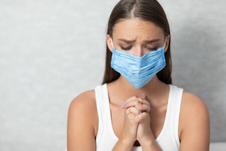 Girl In Medical Mask Praying For End Of Coronavirus Pandemic Standing Over White Background. Free Spaceの写真素材