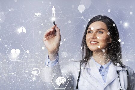 Doctor Lady Holding Stylus Drawing On Invisible Digital Screen Standing Over Gray Studio Background....