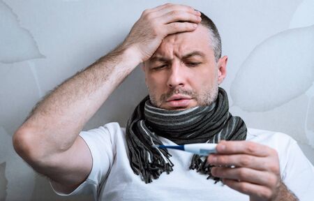 Sick Man Having Fever Measuring Temperature With Thermometer Having Flu Symptoms Lying In Bed At...