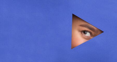 Geometry Concept. Young woman peeking out torn blue paper, copy space for text or promotiomal contentの写真素材