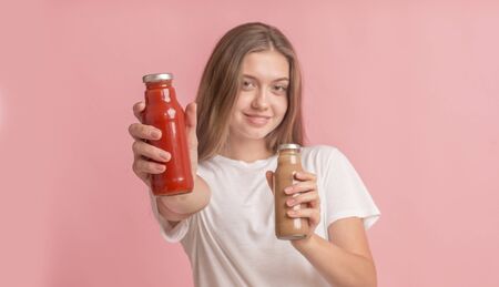 Healthy lifestyle. Young girl holding two detox smoothie over pink background, panoramaの写真素材