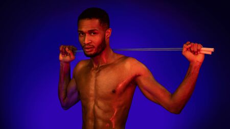 Fitness Workout. African Athlete Guy Holding Jump Rope Standing Over Blue Studio Background With Red...