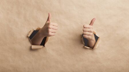Be healthy. Hands showing thumbs up over cardboard wall, safety delivery, panoramaの写真素材