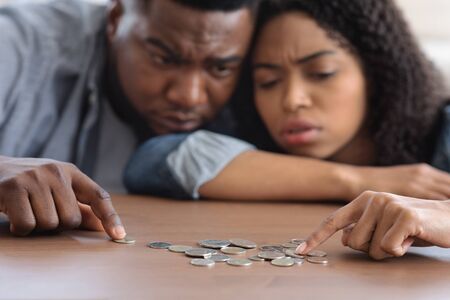 Family Financial Problems. Young Black Couple Counting Remaining Coins On Table, Suffering From Poverty And Absence Of Money, Selective Focusの写真素材