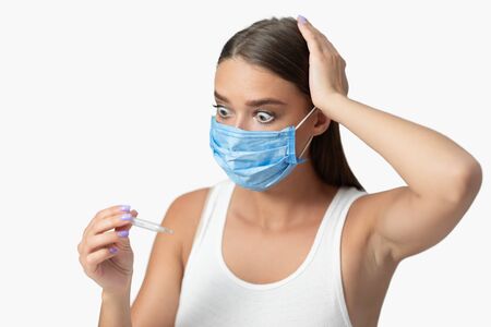 Coronavirus Symptom. Scared Girl Having Fever Looking At Themometer, Posing Over White Background,...