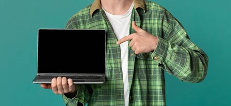 Closeup of unrecognizable guy pointing at laptop with blank screen on color background, space for your design. Panoramaの写真素材