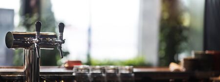 Selective focus on cold beer tap in cafe, blurred background, take away beer, panorama, copy spaceの写真素材