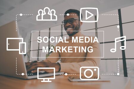 Collage with African American manager working in open space office and social media marketing icons on imaginary screenの写真素材