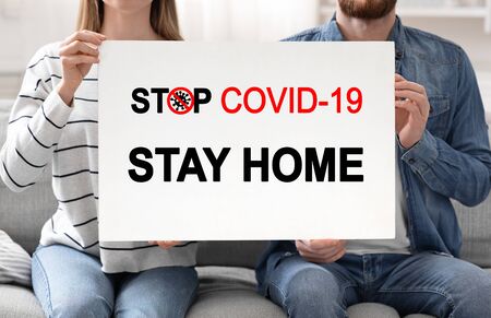 Stay at home concept. Married couple holding poster with text Stop Covid-19の写真素材