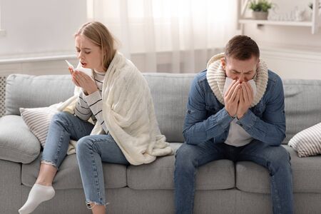 Sick with coronavirus family. Infected man and woman coughing at home interiorの写真素材