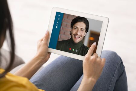 Social distancing and online communication. Young girl chatting with her boyfriend via tablet at home, closeupの写真素材