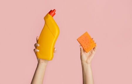 Cleaning service concept. Close up of girl holding toilet desinfectant gel and sponge on pink background, copy spaceの写真素材